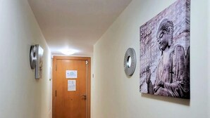 A hallway with a wooden door, a wall-mounted clock, and a Buddha statue. - Belvilla by OYO Apartment in Vera Playa (Vera)
