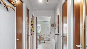 A hallway with wooden doors, a radiator, and a hanging coat rack. - 5 Person Holiday Home in Skjern (Skjern)