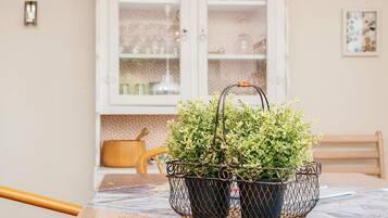 A dining table with a metal plant holder containing green plants.