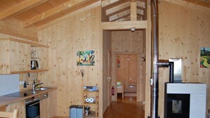 A wooden cabin interior with a kitchen, dining area, and a fireplace. - Fantastic Apartment in Schleching (Schleching)