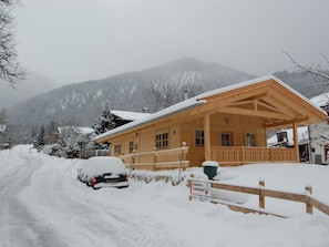 A wooden lodge with a covered porch and a sign indicating it is an 'Elektro-Achental' accommodation. - Fantastic Apartment in Schleching (Schleching)