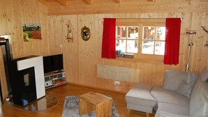 A cozy living room with wooden walls, a grey sofa, a wooden coffee table, and a television. - Fantastic Apartment in Schleching (Schleching)