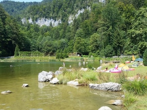 A lakeside setting with a wooden dock, a small cabin, and inflatable rafts. - Fantastic Apartment in Schleching (Schleching)
