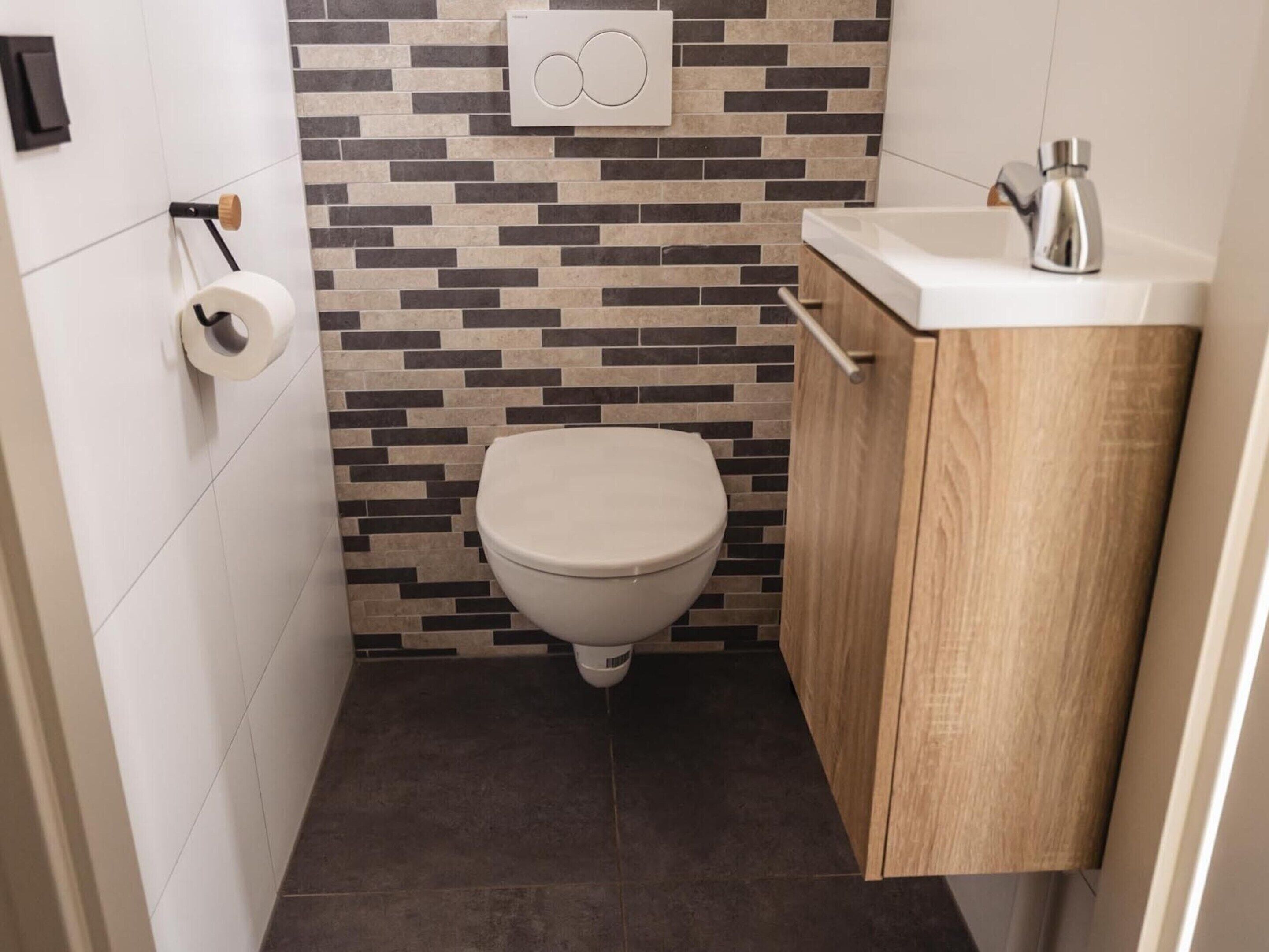 Un baño pequeño con inodoro, lavamanos y ducha.