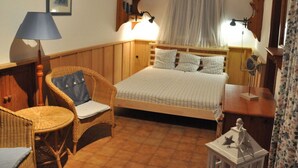 Um quarto aconchegante com cama, poltrona, mesa pequena e luminária.