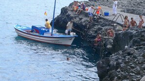 Uma costa rochosa com um pequeno barco atracado perto da areia.