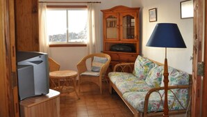Uma sala de estar acolhedora com sofá, cadeiras, televisão e um armário.