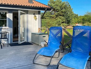 A deck with two blue chairs, a small table, and a white cabinet.