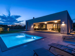A modern house with a swimming pool, outdoor seating, and a well-lit patio area. - Villa Polei Comfortable Holiday Residence (Pula)