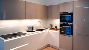 A modern kitchen with a built-in oven, a coffee machine, and a wine bottle on the counter. - Detached House in Zeeland With Scenic Terrace (Wemeldinge)