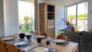 A dining area with a wooden table set for four, surrounded by leather chairs, with a view of greenery outside. - Detached House in Zeeland With Scenic Terrace (Wemeldinge)