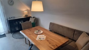 Ein gemütliches Wohnzimmer mit Holztisch, einer Couch, einer Lampe und einer Uhr an der Wand.