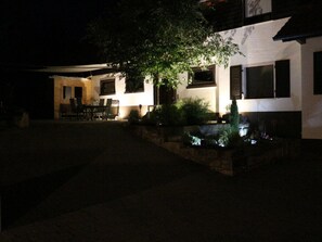 A nighttime view of a building with a well-lit patio area, outdoor seating, and a small water feature. - Pleasant Apartment in Zell am Harmersbach (Zell am Harmersbach)