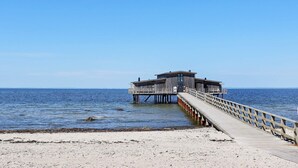 A pier leading to a wooden structure with a flat roof, extending into calm waters. - 4 Star Holiday Home in Bastad (Bastad)