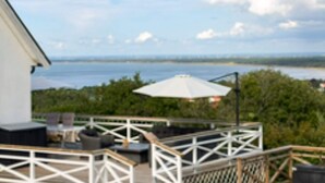 A deck with outdoor furniture and a view of the sea. - 4 Star Holiday Home in Bastad (Bastad)