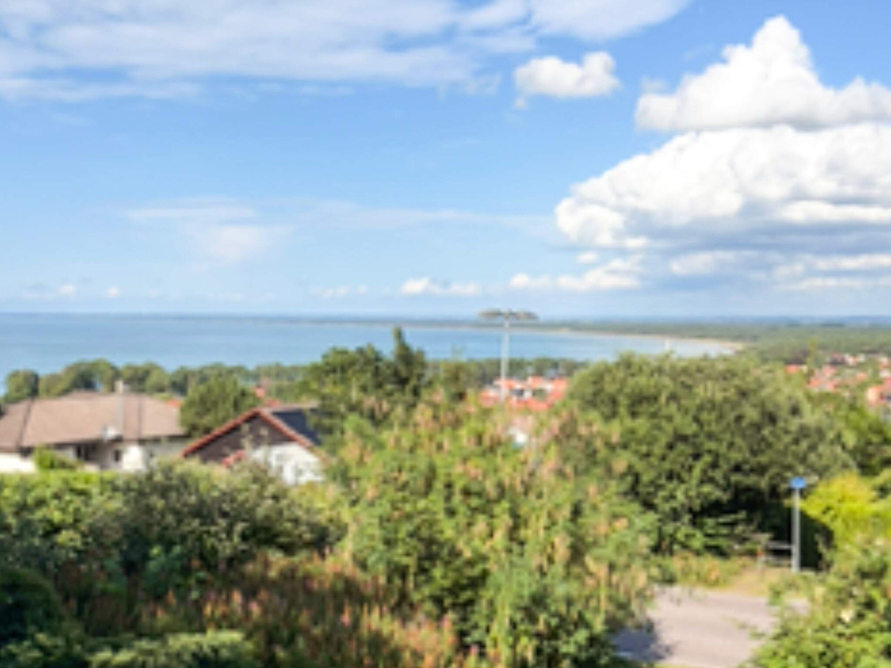 A coastal town with houses, dense greenery, and a clear view of the sea.