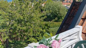 A balcony with a railing, a lawnmower, and pink flowers.