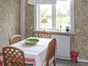 Un coin repas avec une table dressée pour quatre personnes, un radiateur et une fenêtre donnant sur l’extérieur.