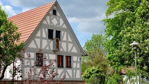 A traditional half-timbered house with a steeply pitched roof, surrounded by lush greenery. - Holiday Home Time out in the Monument (Lohr am Main)