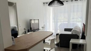 A compact living space with a kitchenette, a dining area, and a seating area with a view of the outdoors. - Très beau T2 3* (office tourisme), grde terrasse, garage proche plage et centre (Cavalaire sur Mer)