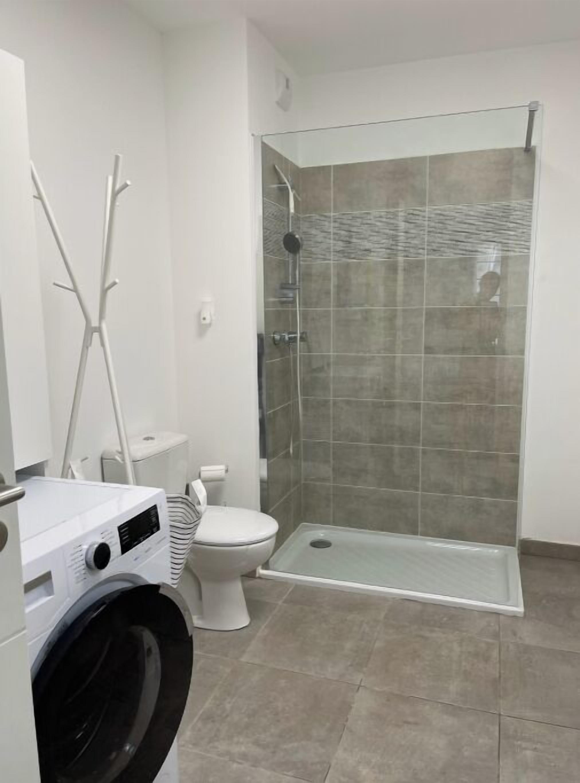 Ein modernes Badezimmer mit Duschkabine, Toilette und Waschmaschine.