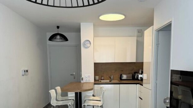 A compact living space with a dining area, kitchenette, and a TV on a cabinet. - Très beau T2 3* (office tourisme), grde terrasse, garage proche plage et centre (Cavalaire sur Mer)