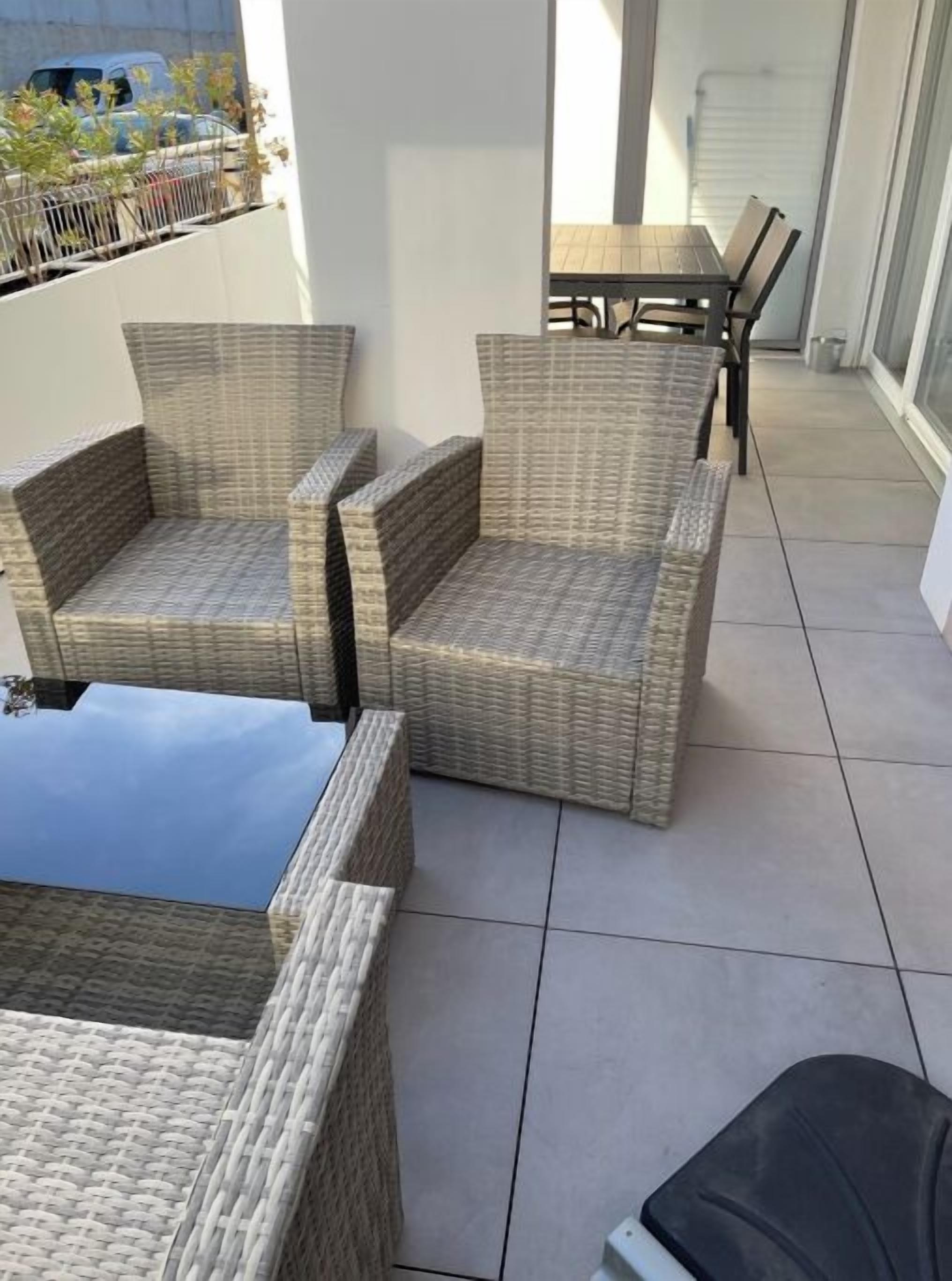 A balcony with wicker furniture, including two chairs and a table.