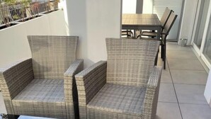 A balcony with wicker furniture, including two chairs and a table. - Très beau T2 3* (office tourisme), grde terrasse, garage proche plage et centre (Cavalaire sur Mer)