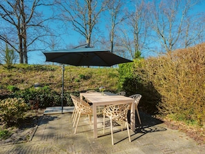 Un patio al aire libre con una mesa y sillas, rodeado de árboles y arbustos.