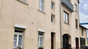 A two-story building with a beige facade and a red base. There are multiple windows, some with shutters, and a visible entrance with a door. - Vinum Comfortable Holiday Residence (Uerzig)