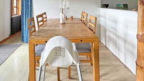 A dining area with a wooden table and six chairs, a white chair with a backrest, and a candelabra on the table. - 5 Person Holiday Home in Nexo (Nexø)