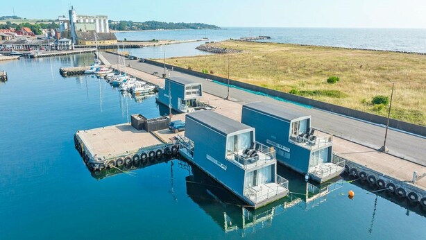 A marina with docked boats, a small building with a flat roof, and a grassy area beside the water. - 5 Person Holiday Home in Nexo (Nexø)
