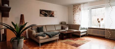 Una sala moderna con sofá, mesa de centro y una planta en maceta.