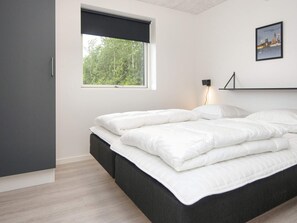 A modern bedroom with a large bed, a window with a view of trees, and a cityscape picture on the wall. - 5 Star Holiday Home in Ansager (Ansager)