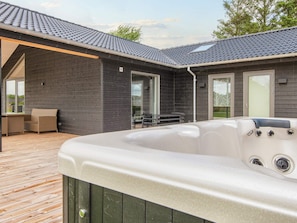 A hot tub on a wooden deck with a dark wooden house in the background. - 5 Star Holiday Home in Ansager (Ansager)