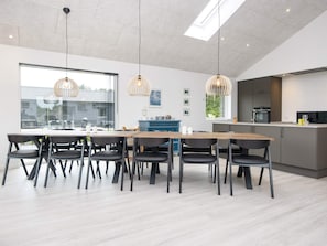 A modern kitchen with a large island, pendant lighting, and a view of the outside. - 5 Star Holiday Home in Ansager (Ansager)