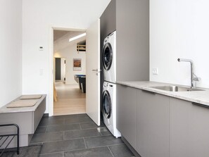 A modern kitchen with a double washing machine, a sink, and a pool table in the background. - 5 Star Holiday Home in Ansager (Ansager)