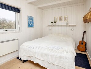 A room with a bed, a guitar, a window with curtains, and a wall with framed pictures. - 4 Star Holiday Home in Blokhus (Blokhus)