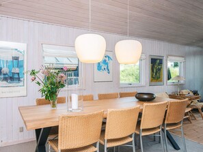 A dining area with a wooden table, wicker chairs, and hanging pendant lights. - 4 Star Holiday Home in Blokhus (Blokhus)