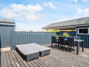 An outdoor patio with a wooden deck, a table with chairs, and a small seating area. - 4 Star Holiday Home in Blokhus (Blokhus)
