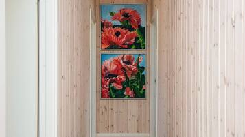 Un pasillo con paneles de madera y dos cuadros enmarcados con motivos florales en la pared.