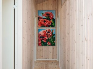 A hallway with wooden paneling and two framed floral paintings on the wall. - 4 Star Holiday Home in Blokhus (Blokhus)