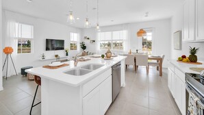 A modern kitchen with a central island, white cabinetry, and pendant lighting.