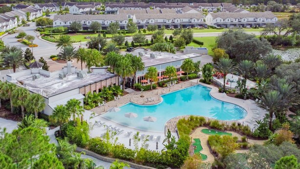 A resort with a large pool, multiple buildings, and lush landscaping.