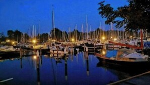 Ein Yachthafen im Abenddämmerung mit vertäuten Booten und Lichterreflexionen auf dem Wasser.