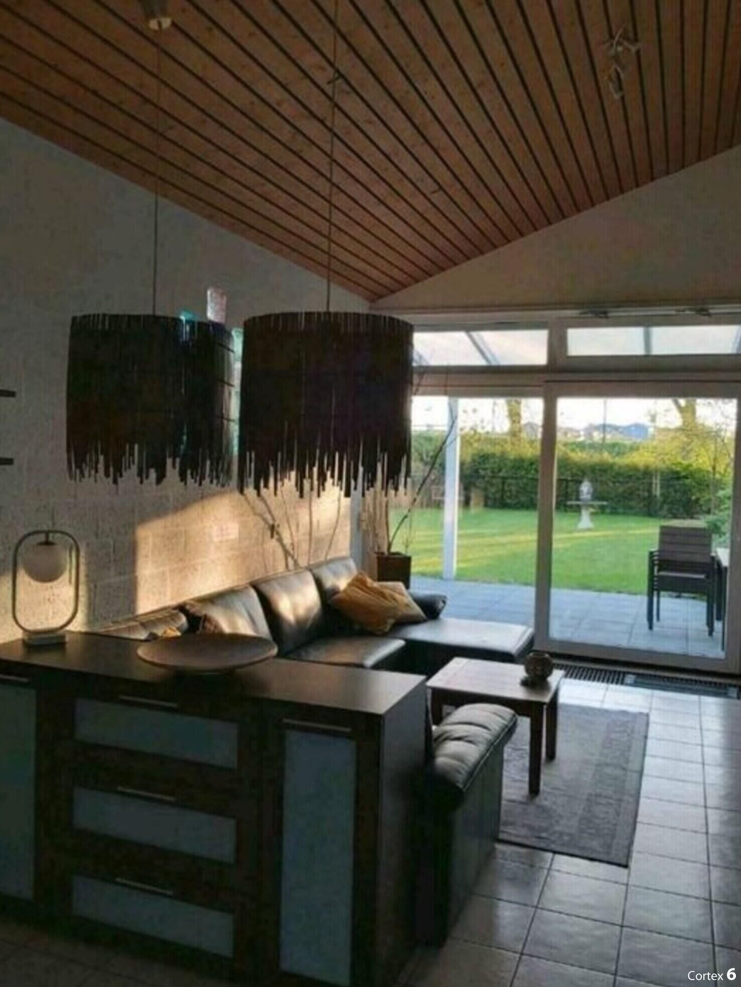 Ein modernes Wohnzimmer mit einer Couch, einem Couchtisch und einem großen Fenster mit Blick auf einen Garten.