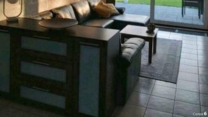 Ein modernes Wohnzimmer mit einer Couch, einem Couchtisch und einem großen Fenster mit Blick auf einen Garten.