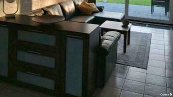 Ein modernes Wohnzimmer mit einer Couch, einem Couchtisch und einem großen Fenster mit Blick auf einen Garten.