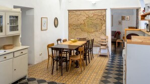 A compact kitchen with a dining area, featuring a map on the wall, wooden furniture, and a checkered floor.