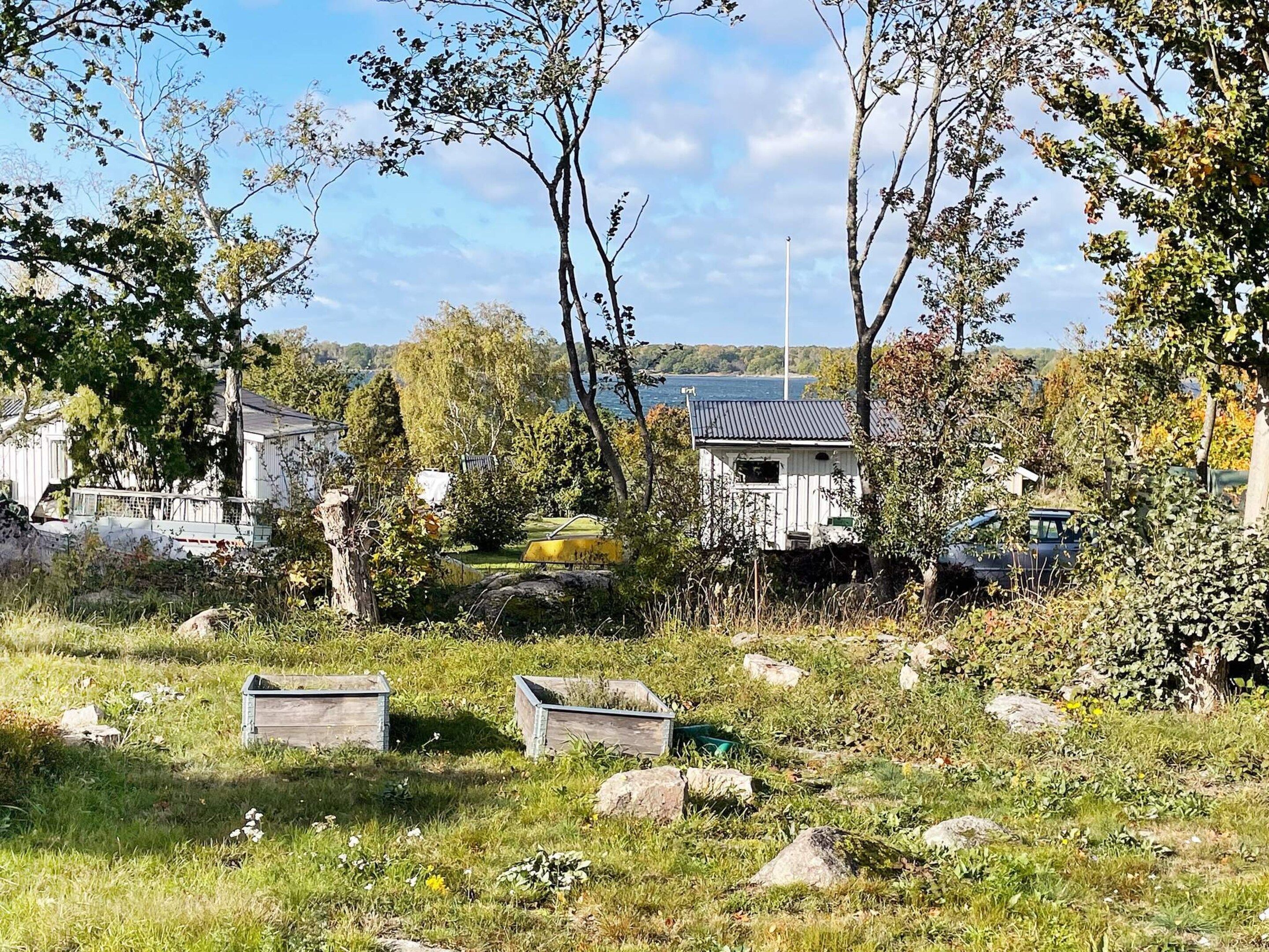 A rural landscape with a white house, a yellow tractor, and a body of water in the background.